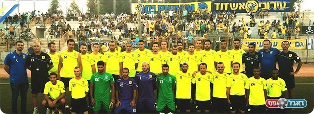 סגל הקבוצה על רקע האוהדים (מכבי עירוני אשדוד)